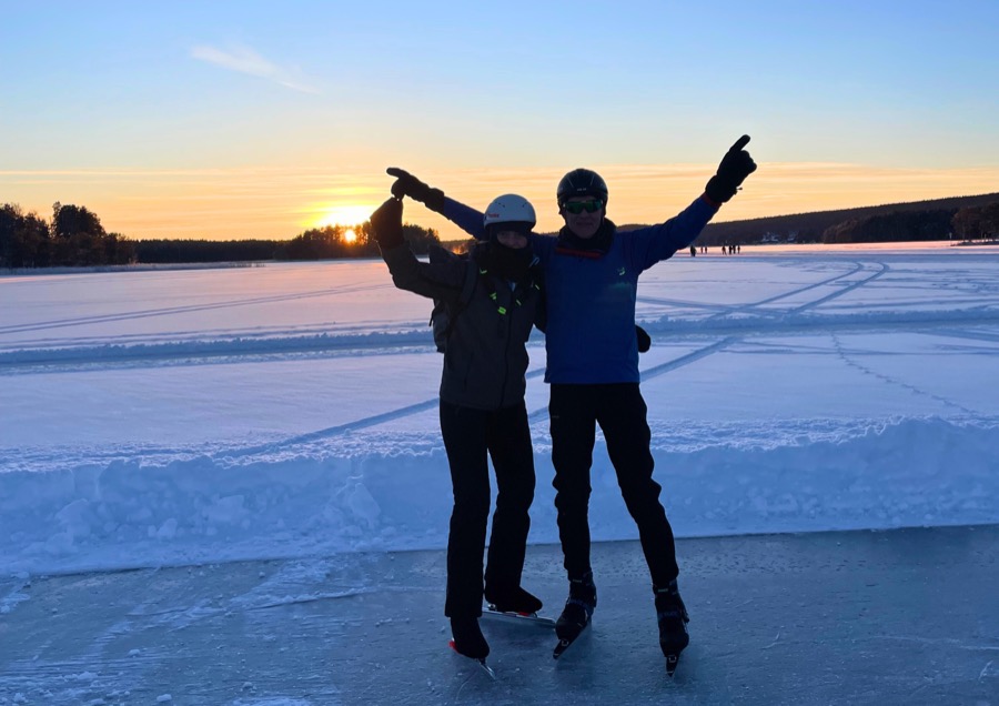Twee schaatsers samen op het ijs bij zonsondergang
