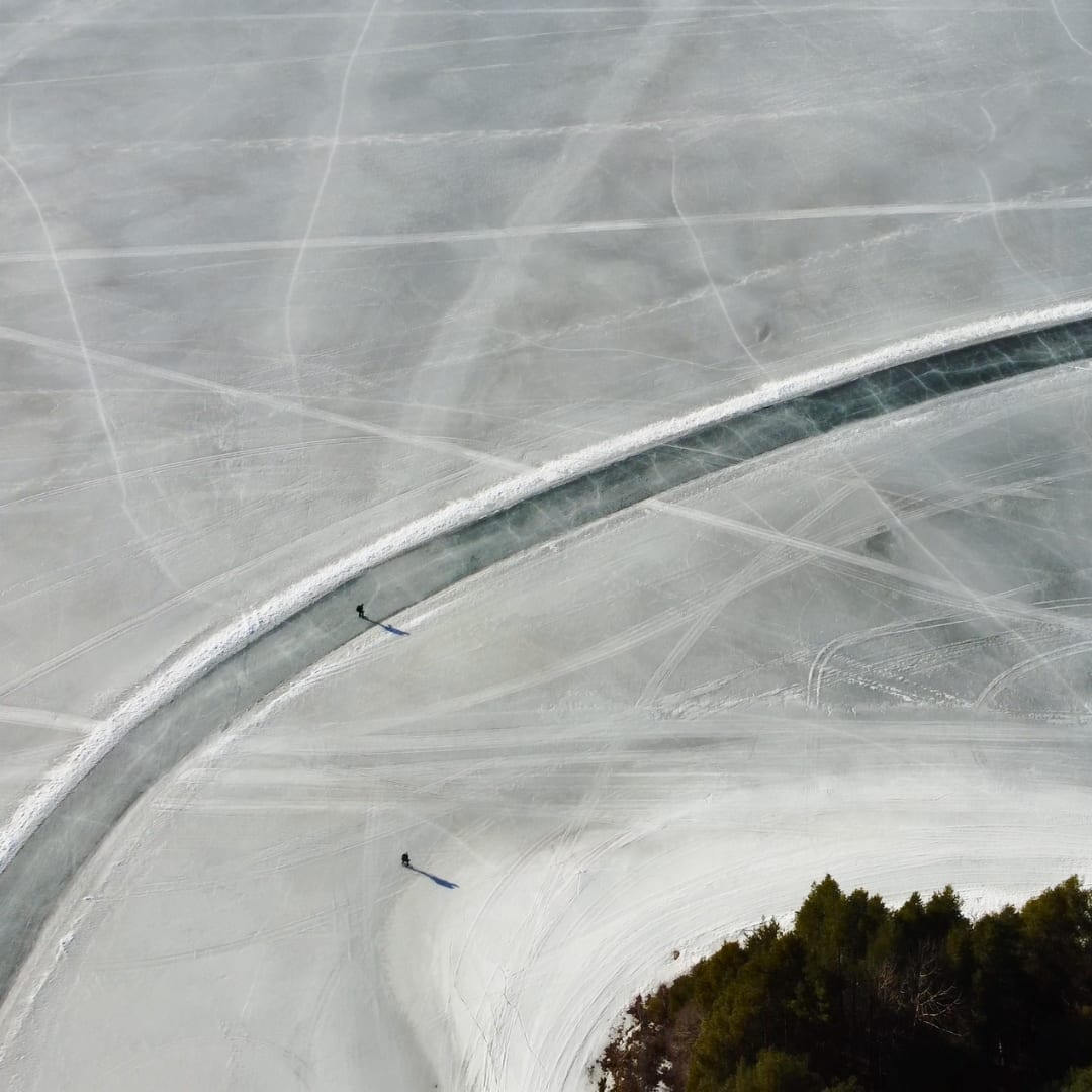 Luchtfoto van een geveegde schaatsbaan die in een bocht over een besneeuwd meer loopt