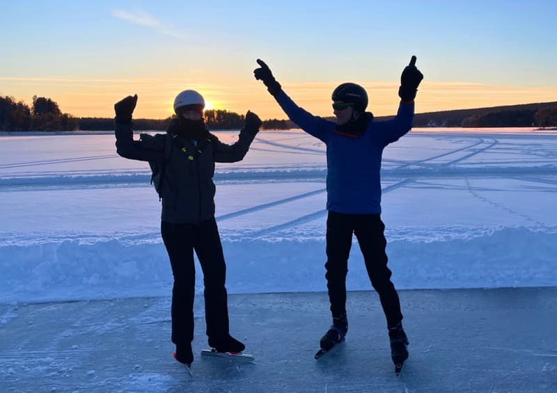 Schaatser met de handen omhoog bij zonsondergang