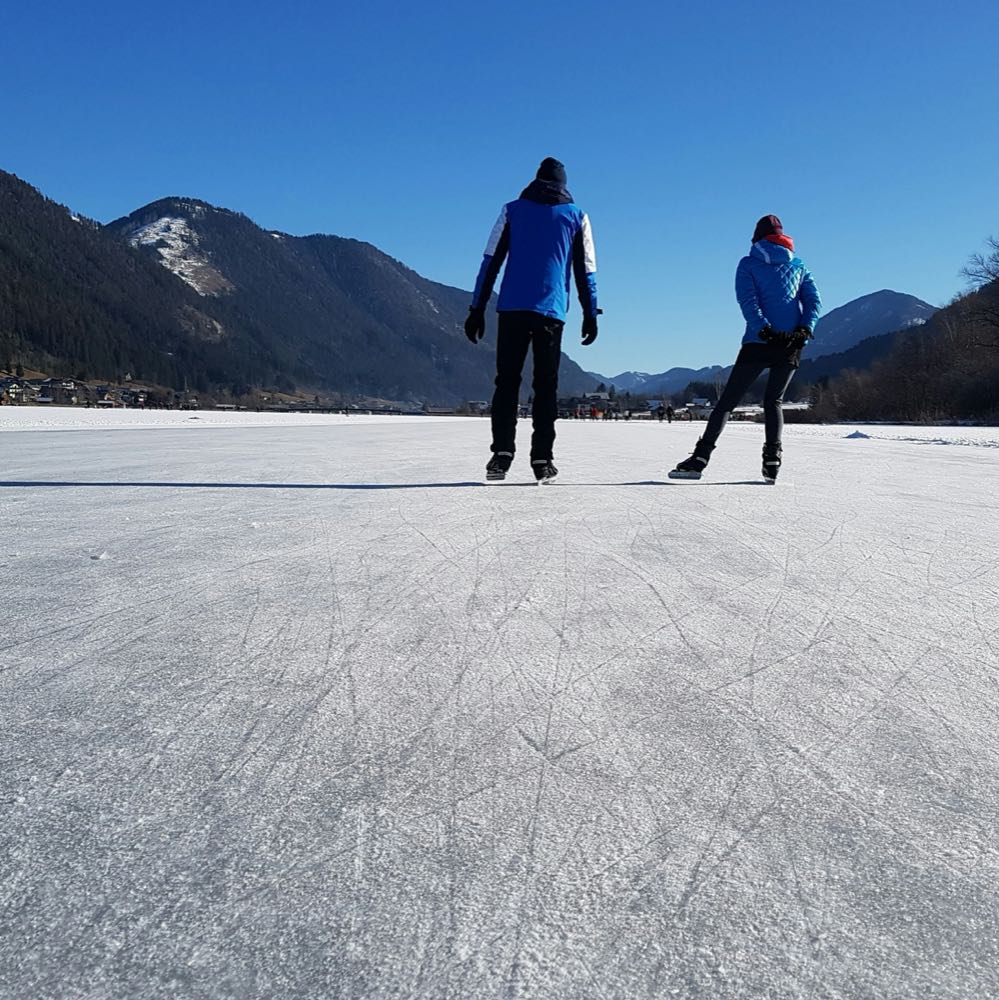 Schaatsers op de Weissensee tussen de bergen